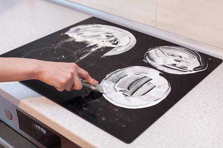 房子清洁家庭主妇清洁和擦亮电饭锅厨房顶部的黑色亮面带泡沫的手玻璃刮背景图片