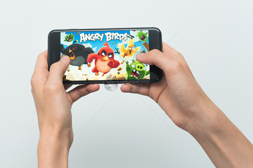 一个年轻人在Iphone8Plus上玩愤怒的小鸟游戏十几岁的男孩手里拿着一部手机图片