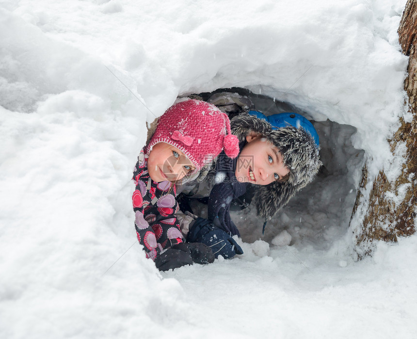 快乐的男孩女看着外面从雪山洞他们图片