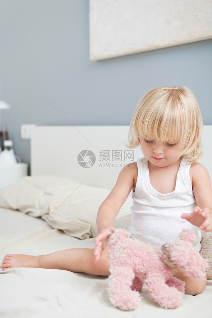年幼的儿女孩坐在父母的床上图片