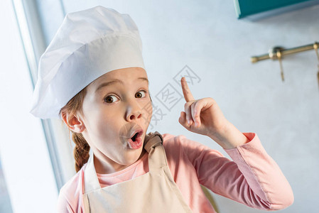 穿着大厨帽的可爱孩子用手指着图片