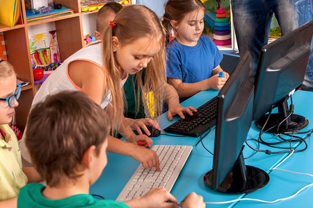 儿童俱乐部的男孩和女孩花很多时间在电脑显示器后面玩耍图片