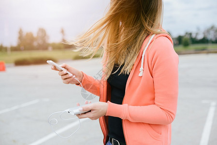 有电话和电源银行玩智能手机游戏的女人不移动的汽车在街上用智能手机玩手图片