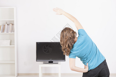 妇女利用屏幕电视指示在家里健身背景图片