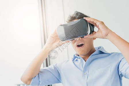 亚洲男子在客厅佩戴虚拟现实眼镜箱头耳机图片