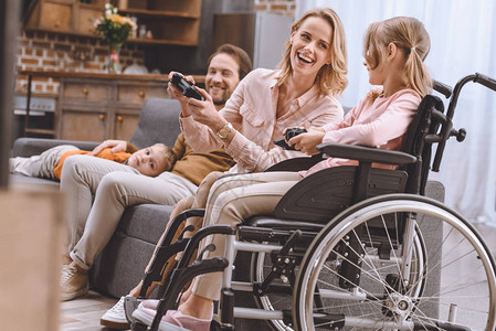 残疾儿童家庭在轮椅上与在家玩游戏棍的残疾图片