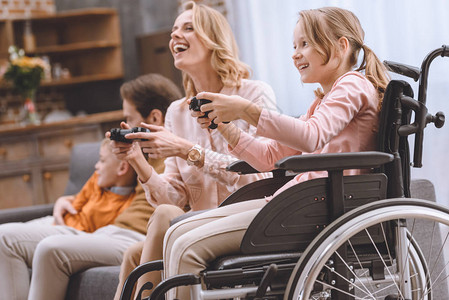 在家与残疾儿童一起玩游戏棍的轮椅残疾人家庭快图片