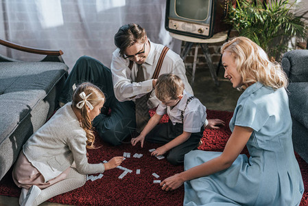 与两个孩子一起在家里玩多米诺游戏的幸福家庭图片
