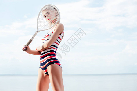 穿反光条纹泳衣的漂亮女孩装扮成网球拍图片