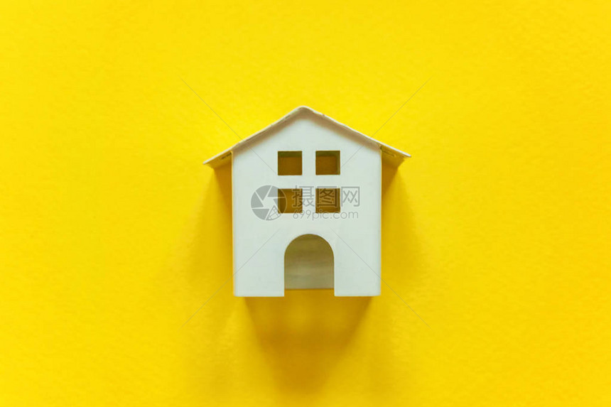 简单的平躺设计与黄色彩纸时尚背景上的微型白色玩具屋抵押财产保险图片