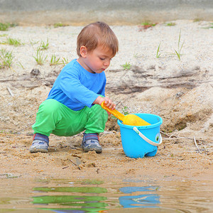 小男孩在沙滩上玩水桶和铁锹图片