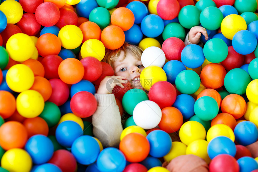 快乐的小孩在多彩的塑料球操场玩耍图片