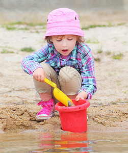 小女孩在沙滩上玩水桶和铁锹图片