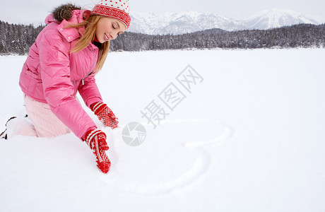 迷人的年轻女子跪在雪山森林风景中的冰冻湖上图片