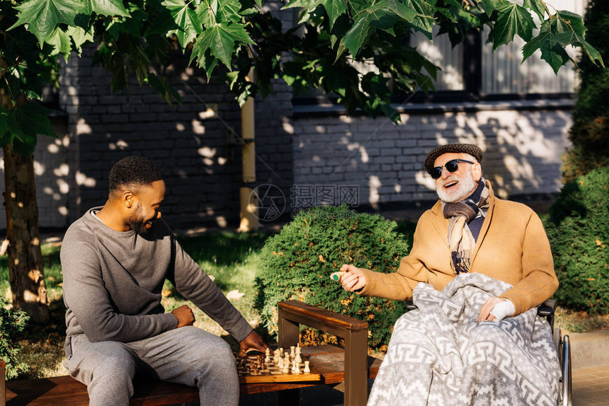 坐在轮椅上和在街上一起下棋的非裔美国康公会图片