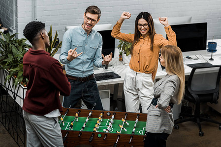 快乐的多元文化商业同事在办公室一起玩桌球图片