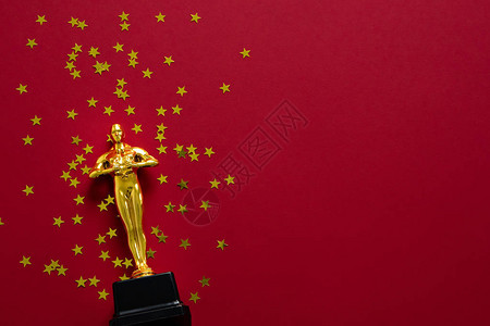 红色背景上有星五彩纸屑的金雕像奖杯图片