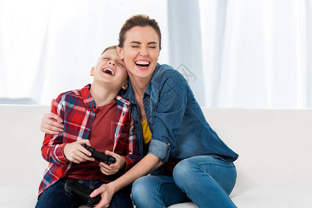 快乐的母亲在玩电子游戏的同时拥抱儿子图片