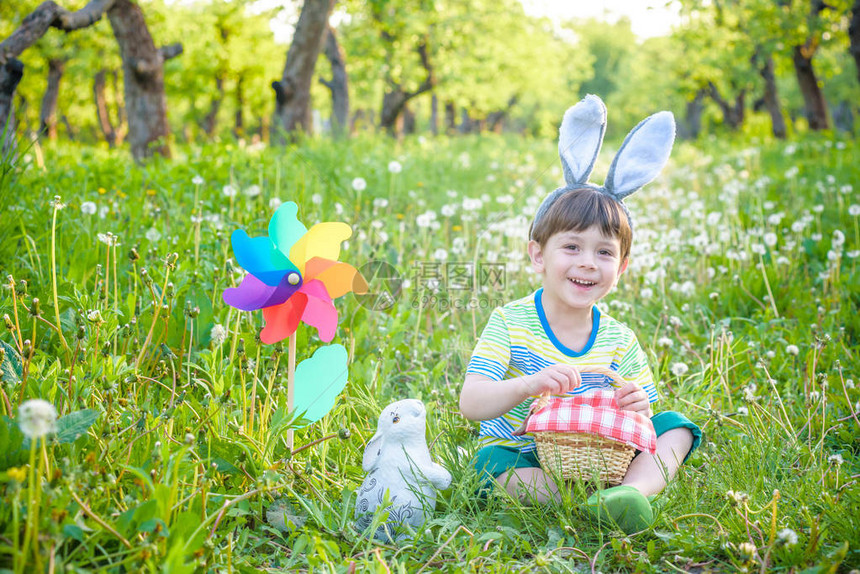 小男孩在春天的花园里寻找复活节彩蛋有传统兔耳朵的可爱小孩微笑快乐可爱的孩子在宗教图片