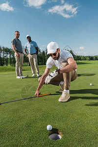 职业高尔夫球手白天在球洞附近看球图片