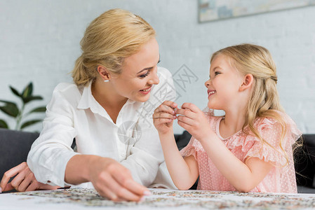 幸福的母亲和女儿在家中玩拼图游戏时图片