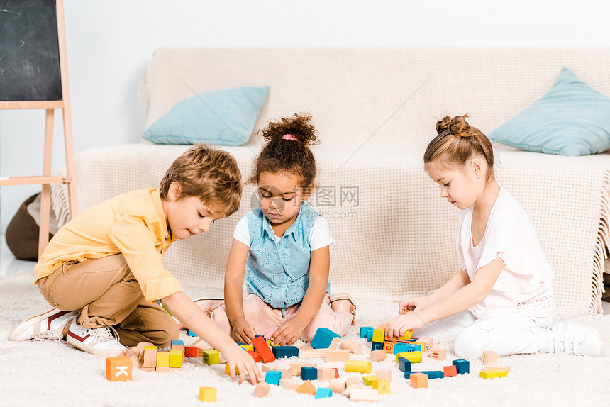 可爱的小孩在地毯上玩彩色方块图片