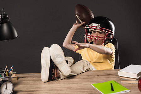 穿着美式橄榄球头盔的男小学生扔球图片