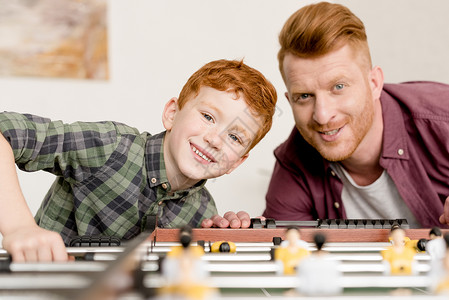 快乐的红发父子在家里一起踢桌上足球时图片