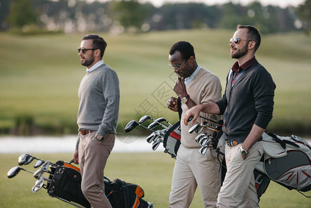 多民族高尔夫球手拿着带高尔夫球杆的袋子在高尔图片