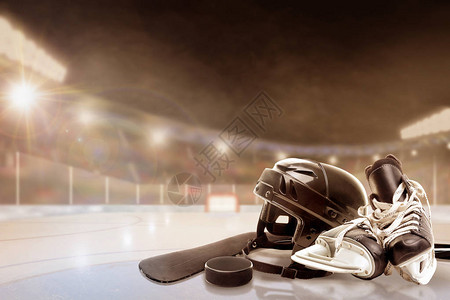 冰球头盔溜冰鞋棍子和冰球在灯火通明的室外体育场图片