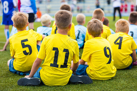 在体育场的儿童足球队在学校足球比赛期间坐在足图片