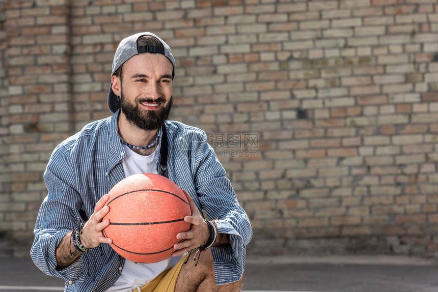 手拿篮球的微笑时髦男人的肖像图片