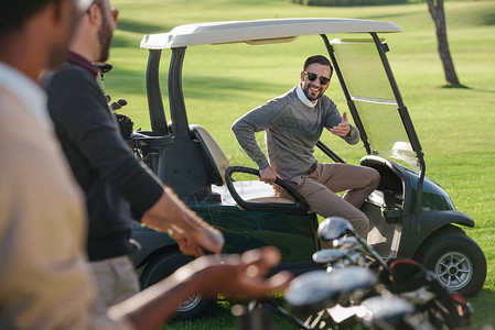 时尚的高尔夫球手坐在高尔夫球场的高尔夫球车图片