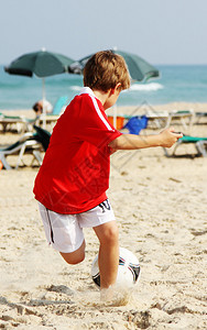 7岁男孩在沙滩上踢足球图片