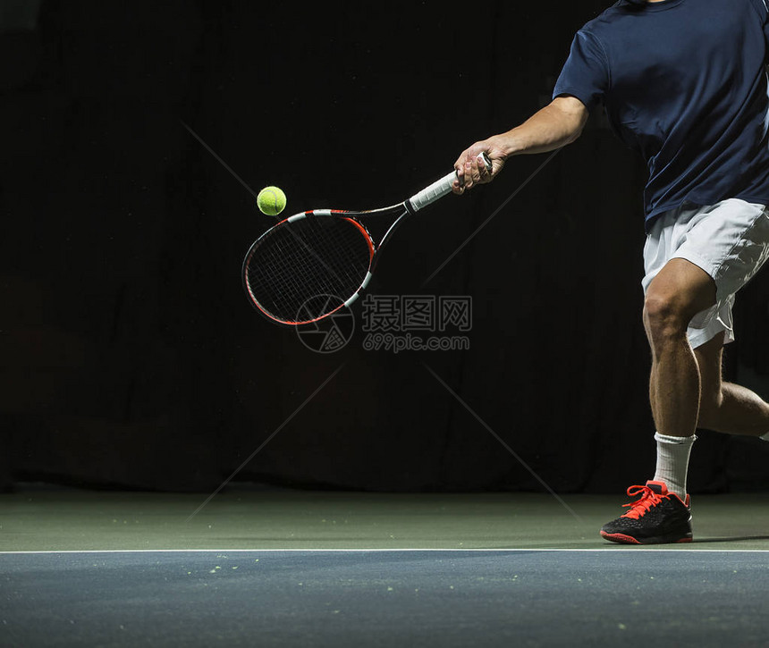 一个男人在网球比赛中挥杆打网球图片