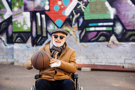 坐在轮椅上有篮球的老年残疾人在背景图片