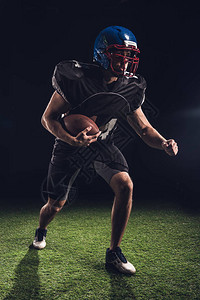 美国足球运动员拿着球站在黑图片