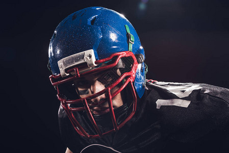 美籍足球运动员戴头盔的特近照片看着在黑色上被图片