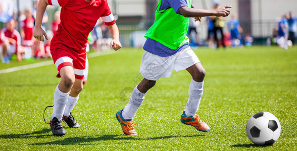 儿童足球比赛儿童足球队在球场上打比赛男孩跑和踢足球青年足图片