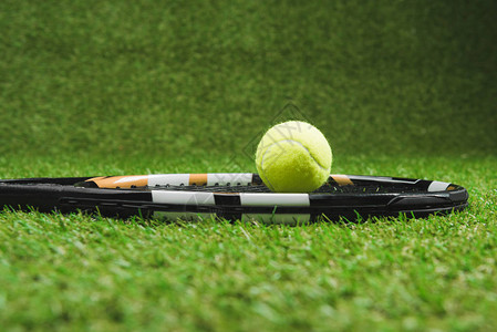绿色草地上网球拍和球的侧视图图片