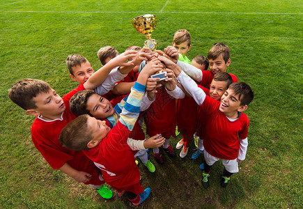 儿童足球足球场上赛后用奖杯庆祝的幼儿球员图片