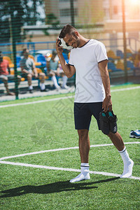带着球和足球靴的微笑足球运动员图片