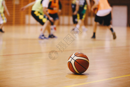 篮球训练比赛背景木制球场地板上的篮球与背景模糊的球员打篮球图片
