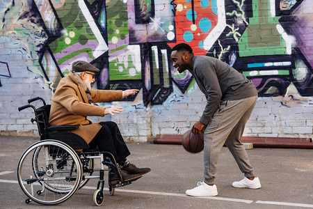 坐在轮椅上的高级残疾人和在街上一起打篮球的图片