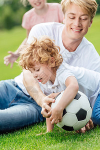 父亲和儿子在公园绿草地上玩足球的快图片