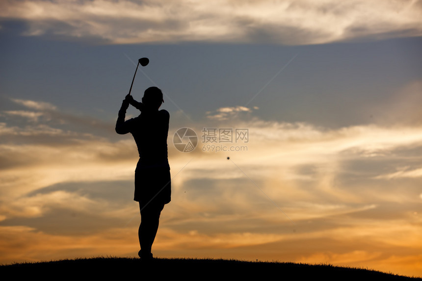 一张日落时女高尔夫球员的轮廓在高尔图片
