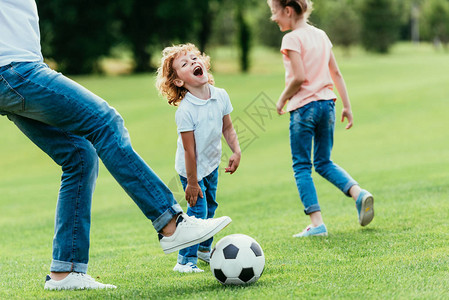 父亲和快乐的孩子一起在公园踢足球图片
