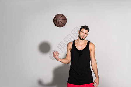 年轻运动员扔篮球看着白色的相机图片