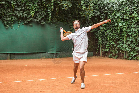 英俊的运动员在网球场上用球拍打网球图片