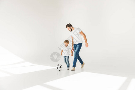 快乐的父亲和儿子与足球一起在白球上踢背景图片